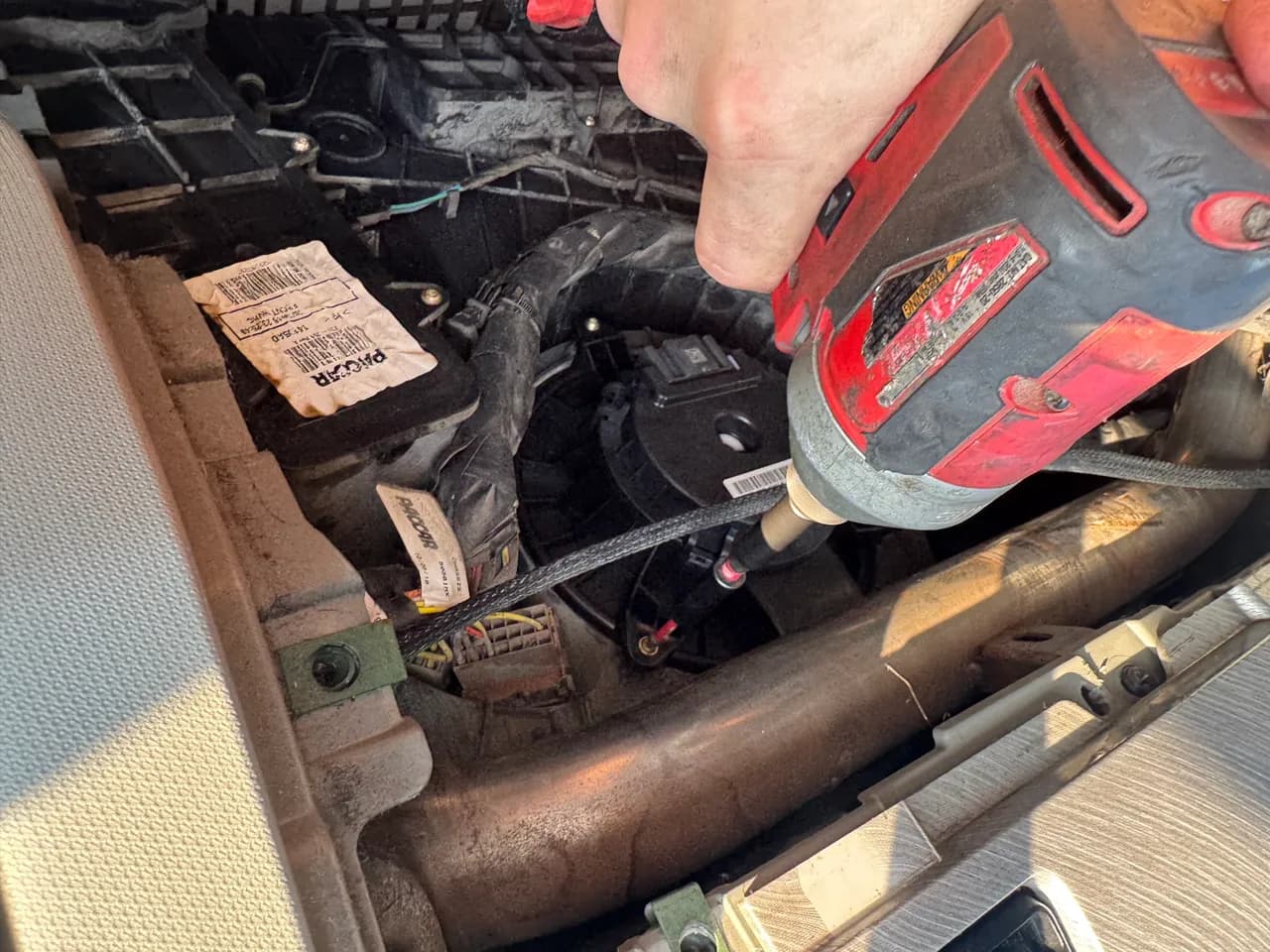 Mechanic using a power tool on an engine exhaust component during a truck repair