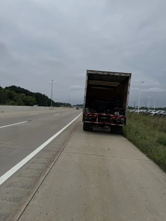 Box truck pulled over on highway shoulder receiving roadside repair service