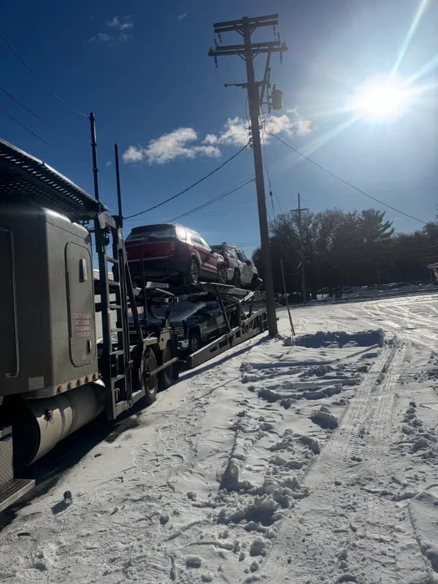 Car-carrier trailer on a snowy highway shoulder during a roadside assistance call